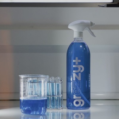 Frasco pulverizador azul com tampo branco e béquer com tubos de ensaio com líquido azul.