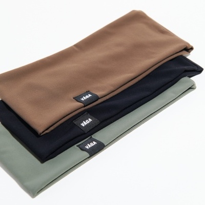 Três peças de tecido dobradas em castanho claro, preto e verde claro com etiquetas V-MAR