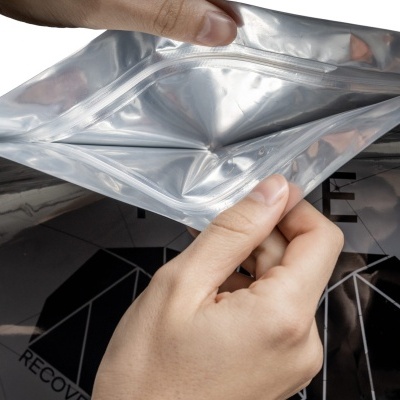 Mãos a abrir embalagem plástica prateada com interior transparente