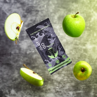 Pacote preto com design gráfico GLUCO 90 rodeado por maçãs verdes num fundo cinzento.