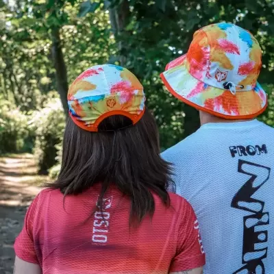 Duas pessoas com chapéus tie-dye coloridos em caminho florestal