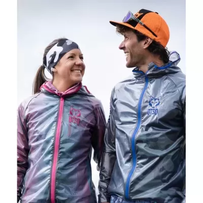 Homem e mulher sorridentes com casacos desportivos impermeáveis UT50, faixa de cabeça e boné com óculos