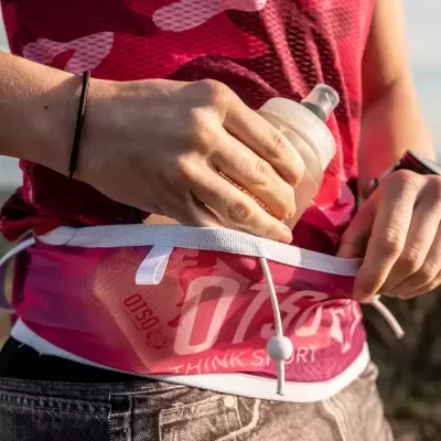 Pessoa a guardar garrafa em cinto desportivo rosa com inscrições