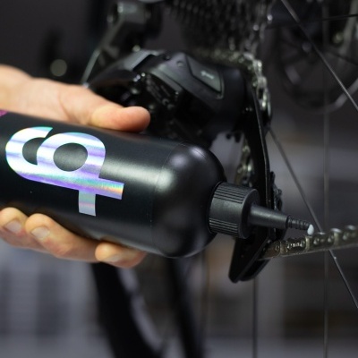 Frasco preto com tampa em bico a ser aplicado em corrente de bicicleta branca