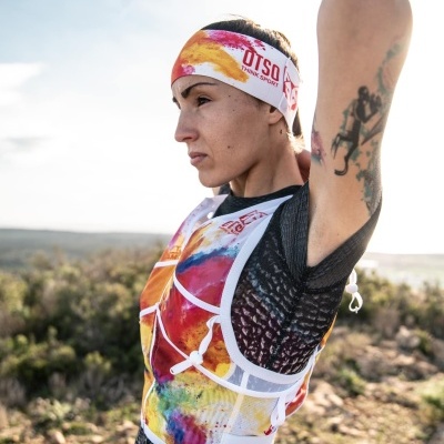 Pessoa com colete e faixa de cabeça coloridos e texto OTSO em ambiente natural