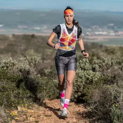 Mulher a correr em trilha com roupa desportiva colorida e fita de cabelo combinando