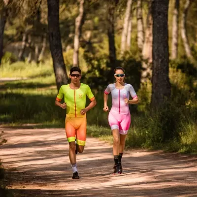 Dois atletas a correr numa floresta com fatos coloridos e óculos escuros.