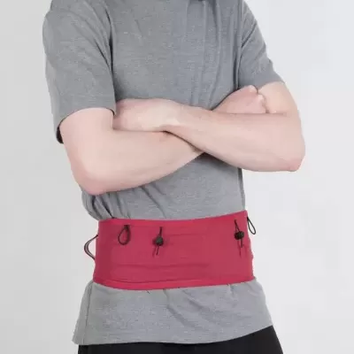 Pessoa com t-shirt cinza, calças pretas e cinto vermelho com cordões na cintura.