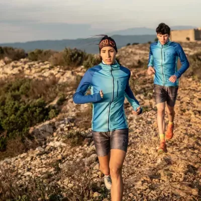 Pessoas a correr em trilho rochoso com roupas técnicas azuis e calções escuros