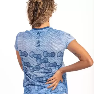 Pessoa de costas usando t-shirt azul claro estampada com laços e texto Hello Kitty.