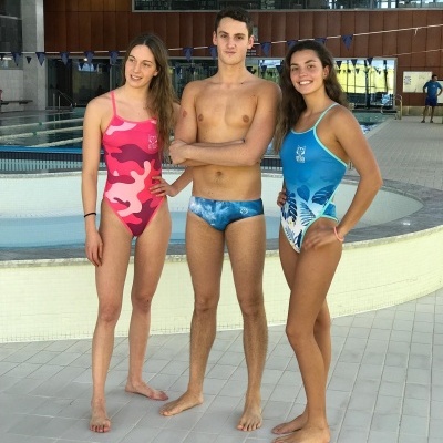 Três pessoas em fatos de banho junto à piscina interior