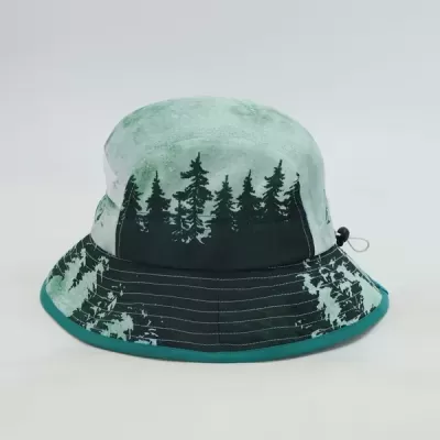 Chapéu de balde com padrão de árvores em tons de verde e preto