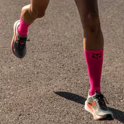 Pernas a correr com meias cor-de-rosa e ténis cinzentos com detalhes laranja