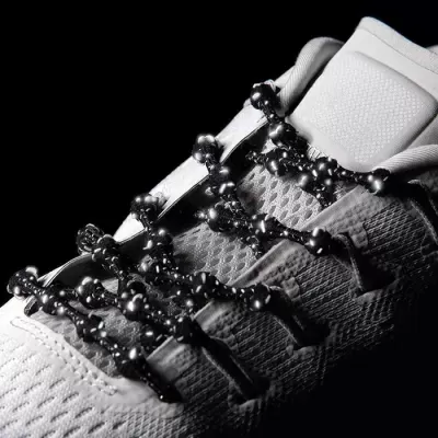 Ténis brancos com atacadores pretos decorados com bolas negras