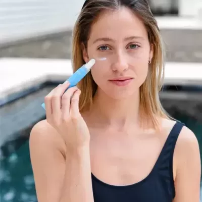 Mulher a aplicar creme facial junto a piscina