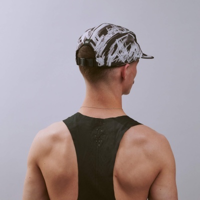 Boné desportivo preto e branco com padrão abstrato visto de trás numa pessoa com regata preta.