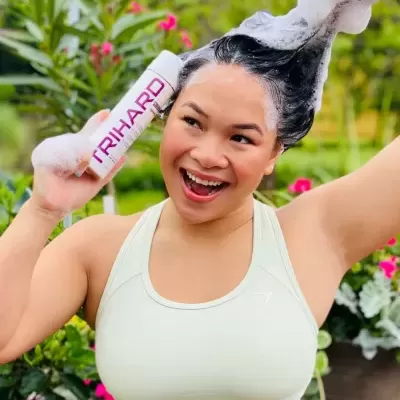 Mulher a lavar o cabelo com espuma e a segurar um produto chamado RIHARD, com vegetação ao fundo.