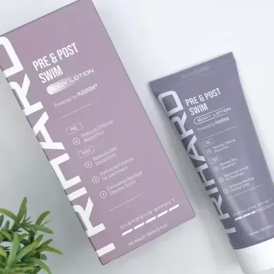 Produto TRIHARD Body Lotion lilás ao lado de caixa lilás e planta verde