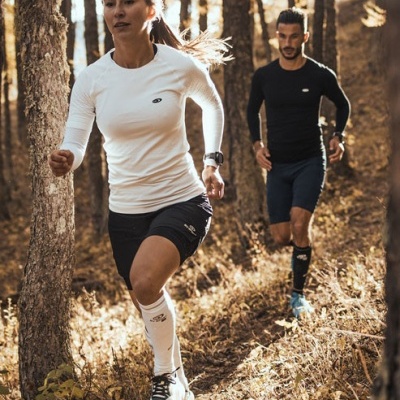 Duas pessoas a correr em roupas desportivas na floresta