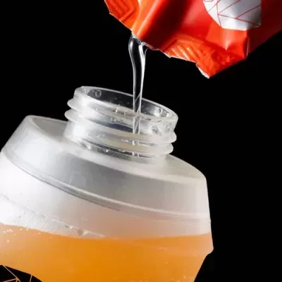 Garrafa plástica translúcida a ser preenchida com líquido de embalagem laranja