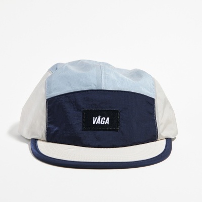 Boné de tecido azul claro, azul escuro e bege com texto VÁGA na frente