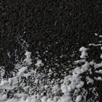 Superfície preta com espuma branca irregular