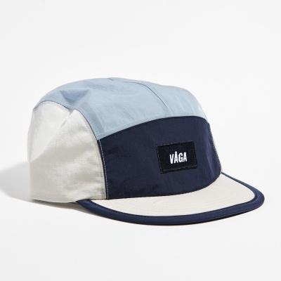 Boné de tecido azul claro, azul escuro e bege com etiqueta 'VAGA'