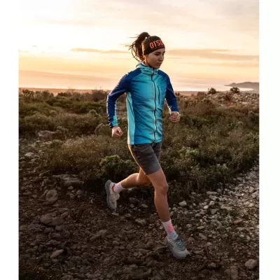Mulher a correr em trilho com casaco azul e faixa OTOSO