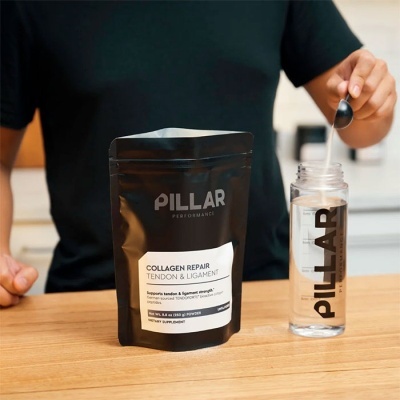 Pacote e garrafa do suplemento alimentar PILLAR sobre mesa de madeira com pessoa ao fundo