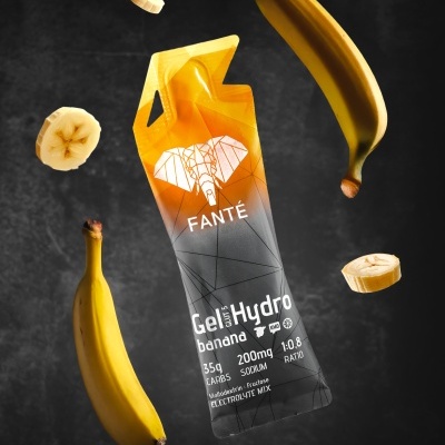 Embalagem de gel hidro com design laranja e cinza, rodeada por bananas e rodelas de banana