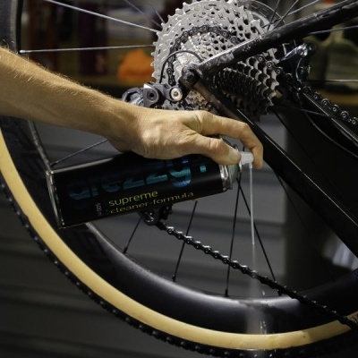 Bicicleta preta com roda bege e spray de limpeza aplicado no cassete