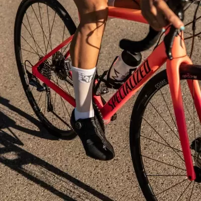 Bicicleta de estrada Specialized vermelha e rosa com ciclista e garrafa de água