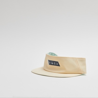 Viseira bege com etiqueta preta 'VÄGA' sobre superfície branca