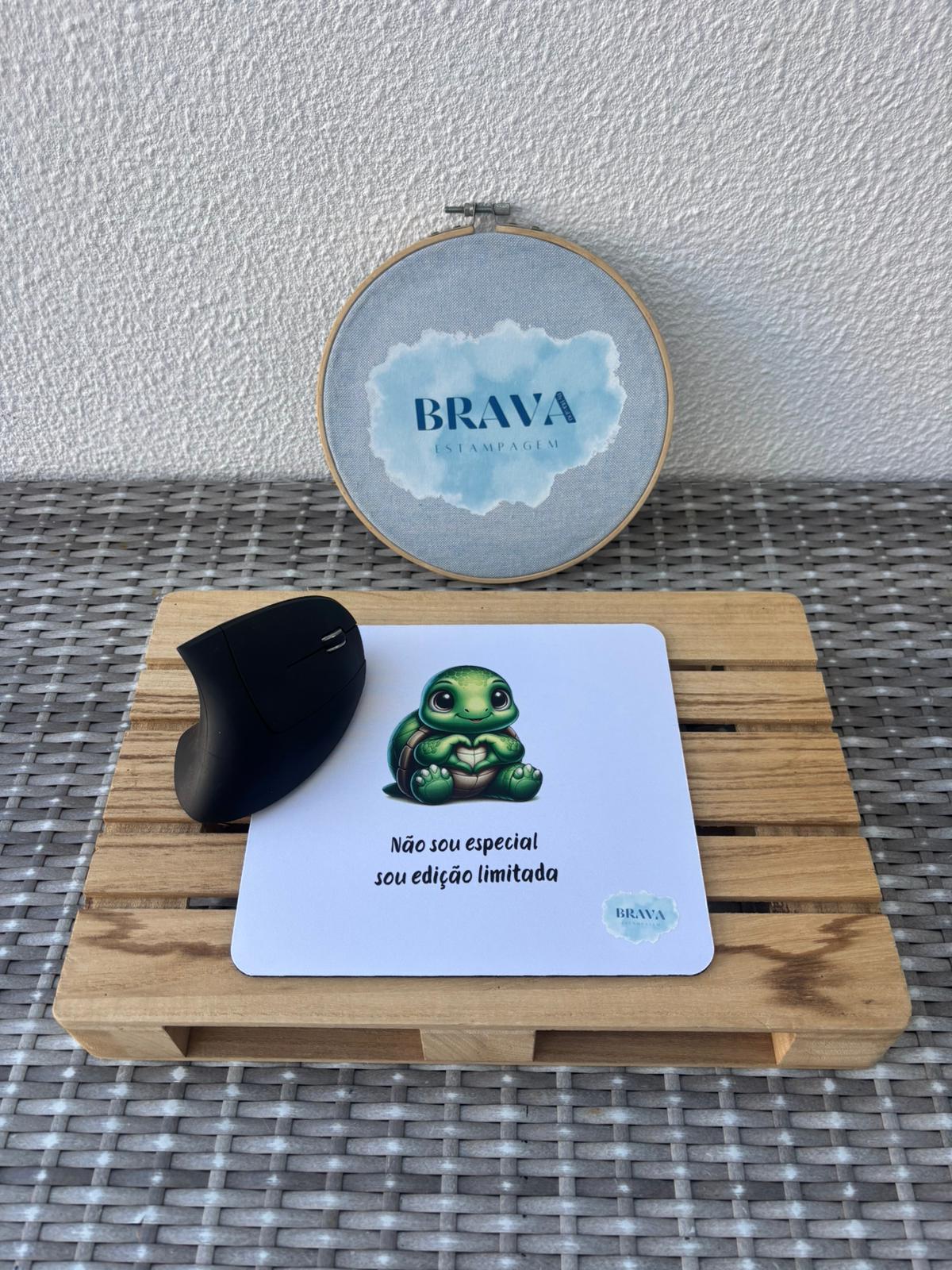 Base para Rato PC Tapete de rato branco com tartaruga e texto em português junto a rato preto ergonómico sobre base de madeira.