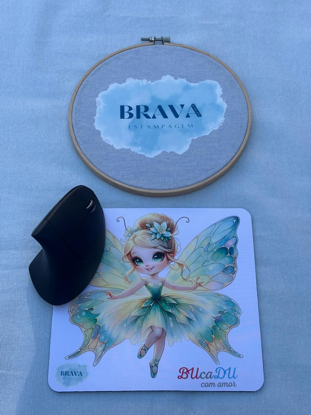 Base para Rato PC Rato vertical preto sobre tapete de rato com fada colorida e bastidor com tecido azul claro e texto BRAVA ESTAMPAGEM