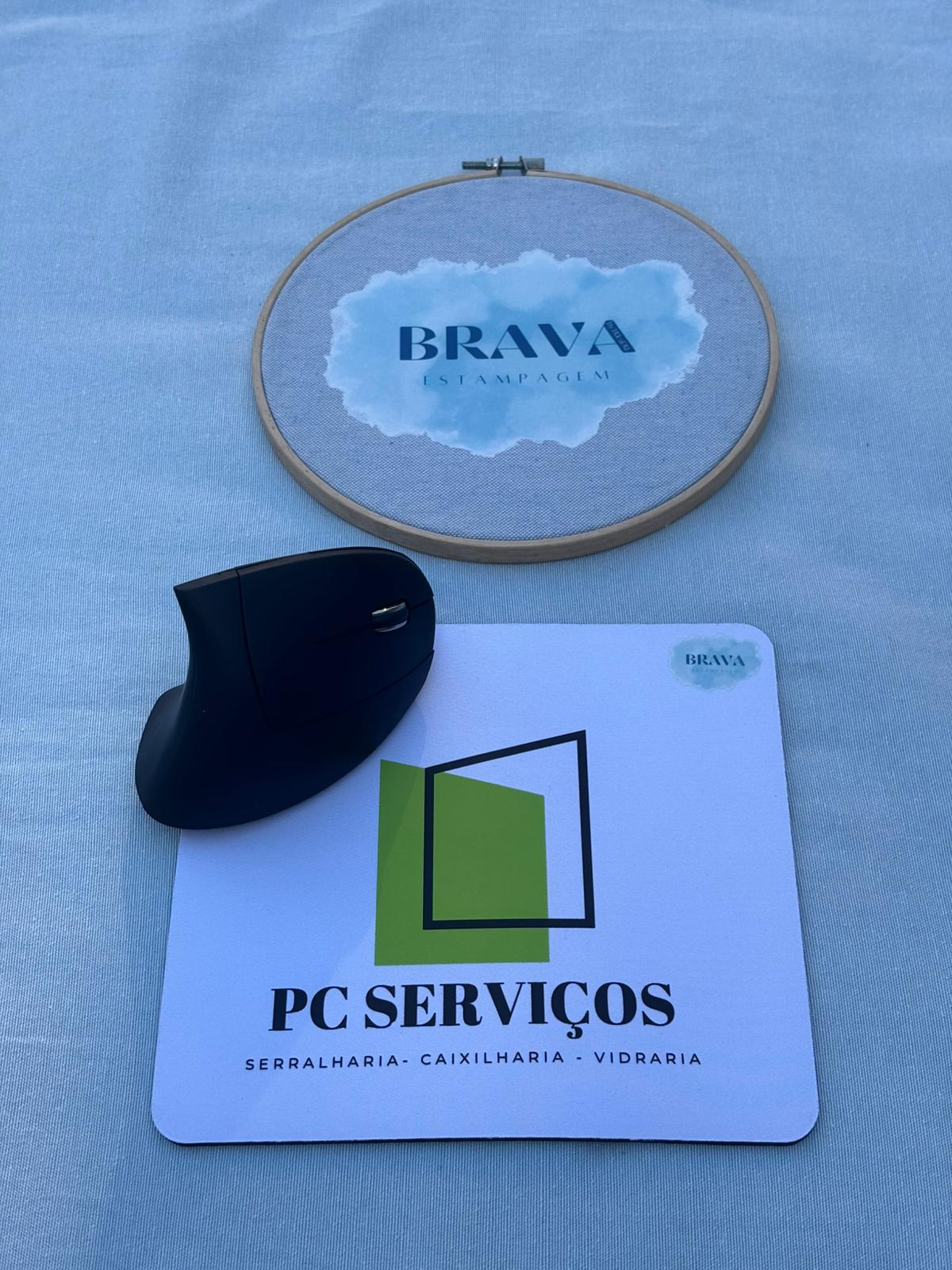 Base para Rato PC Rato ergonómico preto com tapete de rato branco e bastidor de bordado em fundo azul-claro.