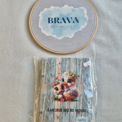 Produto têxtil com estampa de aves e texto A MELHOR AVÓ DO MUNDO em embalagem plástica