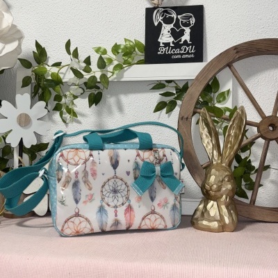 Bolsa com padrão de filtros dos sonhos e penas em mesa com decoração rústica e escultura de coelho