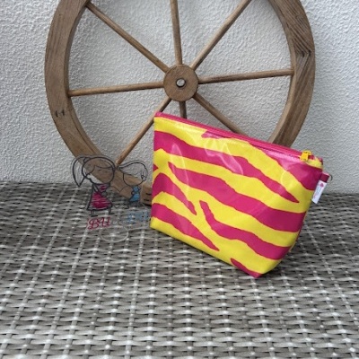 Bolsa pequena multicolor com padrão de riscas colocada sobre superfície cinzenta com roda de madeira ao fundo