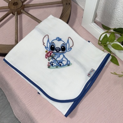 Manta branca com bordado azul de personagem segurando flor