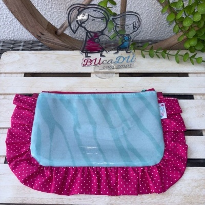 Bolsa azul claro zebrada com bolsa vermelha de bolinhas brancas em superfície de madeira branca