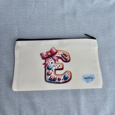Estojo de tecido bege com letra E decorativa tipo biscoito e etiqueta Brava