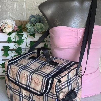 Bolsa quadrada com padrão xadrez bege e preto com alça preta e laço preto ao lado de manequim vestindo vestido rosa