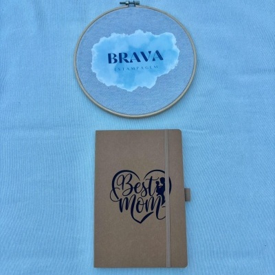 Caderno castanho Best Mom e bastidor com etiqueta BRAVA ESTAMPAGEM sobre tecido azul