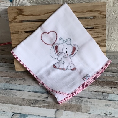 Pano de cozinha branco com bordado de elefante cinzento segurando balão em forma de coração, bordas com bolinhas vermelhas.