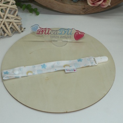 Tira para chupeta branca com padrão de estrelas e luas azuis e amarelas, em fundo branco.