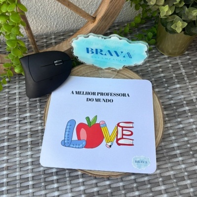 Tapete de rato branco com design colorido e texto para professora, sobre mesa de vime com elementos decorativos
