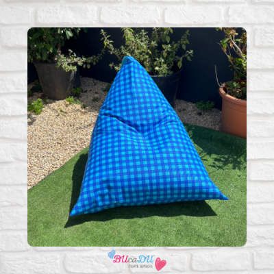 Pufe triangular azul com padrão xadrez em jardim com plantas e relva artificial