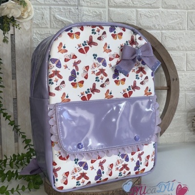 Mochila lilás com padrão de borboletas coloridas e laço decorativo