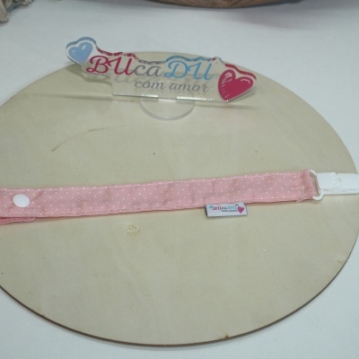 Acessório de tecido rosa com padrão de pontos brancos e placa transparente com texto BUcaDU com amor